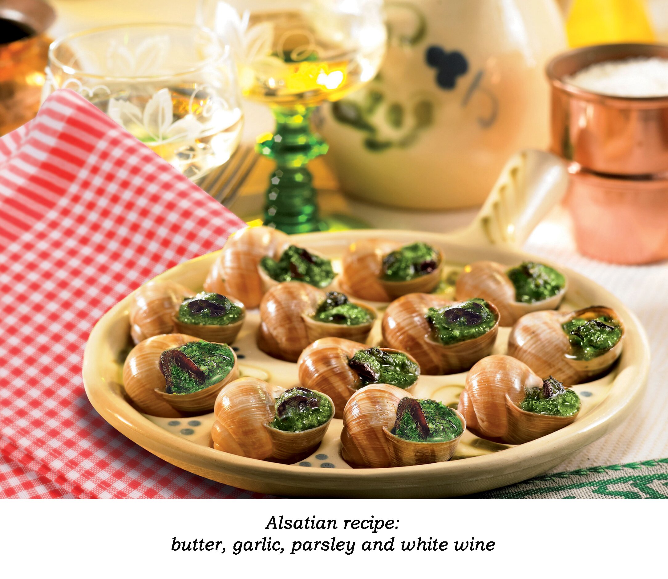 A wooden plate placed on a red-white plaid napkin with some escargots Alsatian recipe. Decorated with a glass of white wine