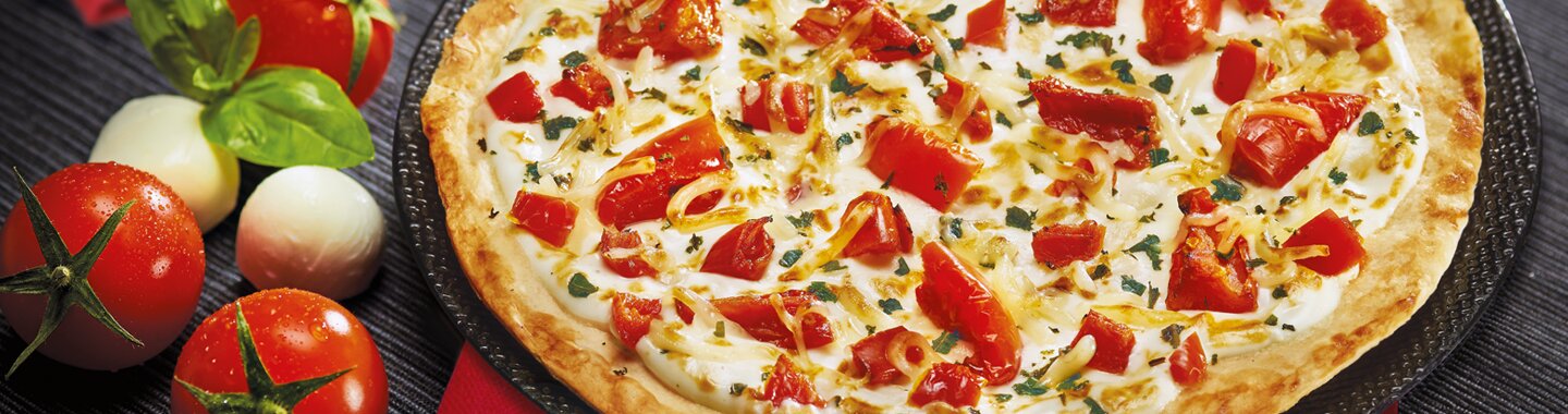 Une tarte fine avec des tomates, du basilic et du mozzarella